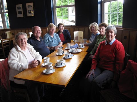 group of people sat at table having tea and coffee